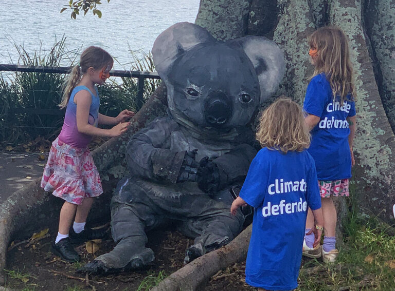 koala puppet sits under a tree with kids looking on