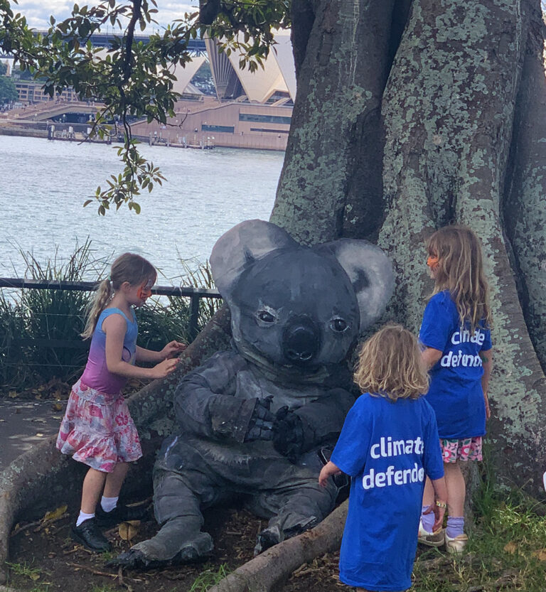 koala puppet sits under a tree with kids looking on